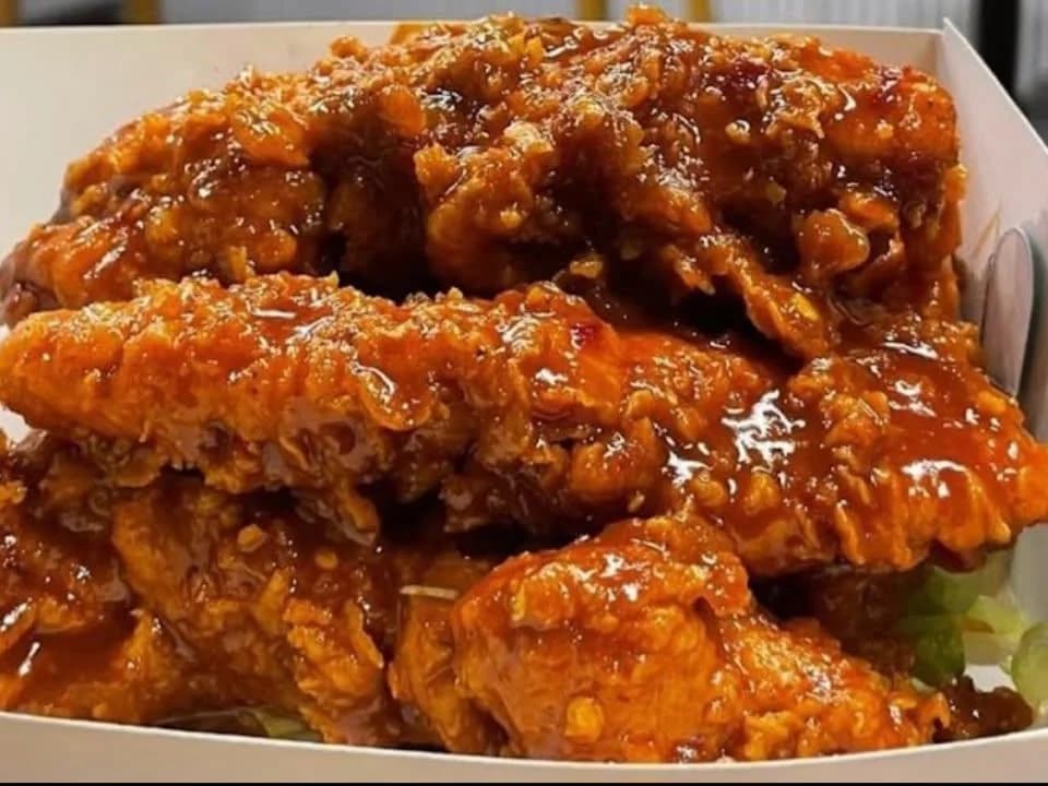 Hot Honey Hustlers - crispy fried chicken tenders glazed in sticky hot honey, stacked in a takeaway box, from Ashville Hot Chicken, JLT Dubai