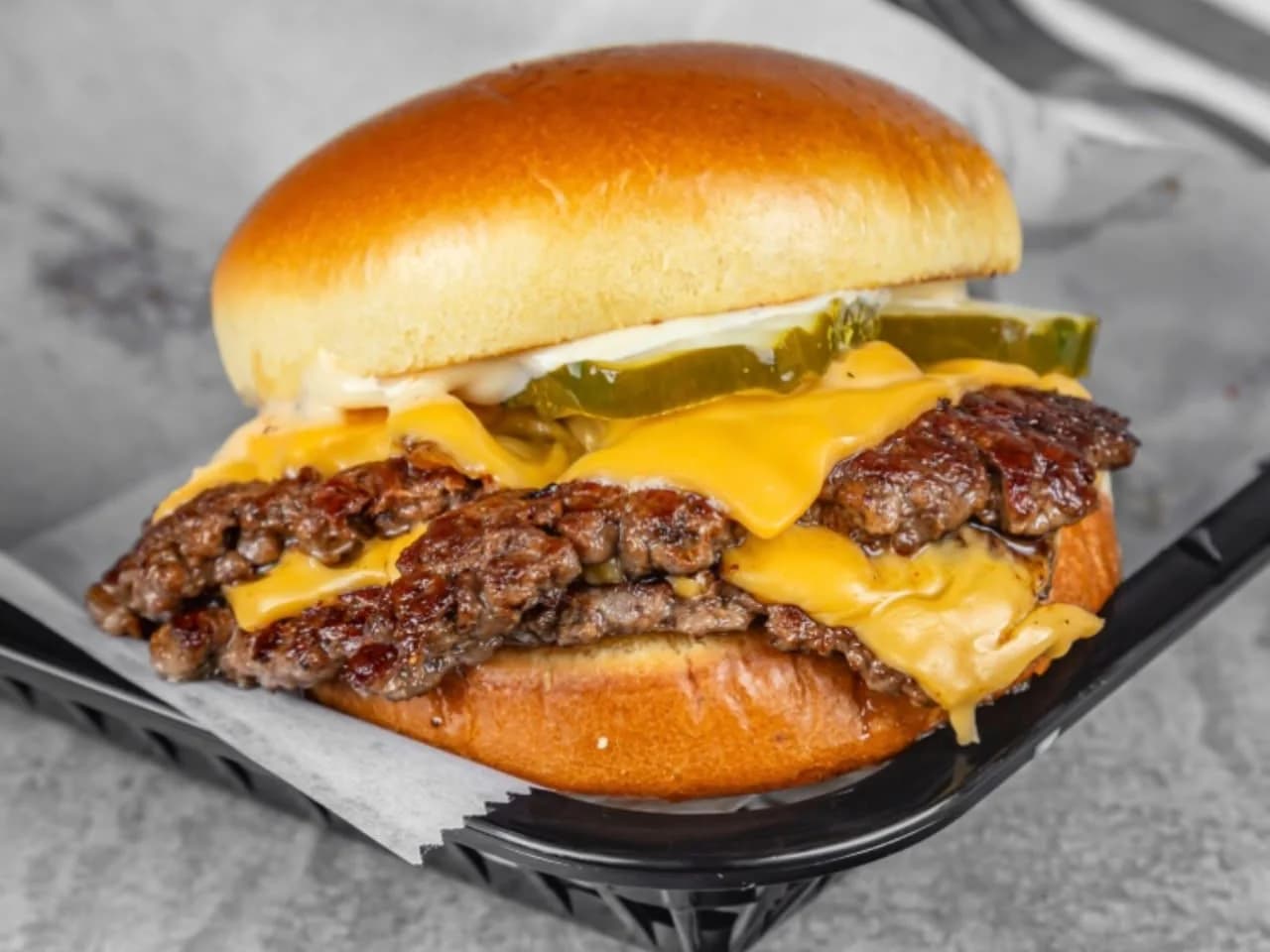 Smashddd - two smashed beef patties with melted american cheese and pickles in a brioche bun, in a basket, from Ashville Hot Chicken, JLT Dubai