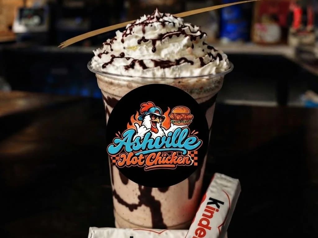 Thick Shakes - a Kinder Bueno thick shake topped with whipped cream and chocolate drizzle in a branded cup, Kinder bars beside it, from Ashville Hot Chicken, JLT Dubai